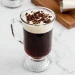 Irish Coffee Drink with layered cream and chocolate shavings on top in tall glass with handle.