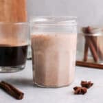 Jar of homemade pumpkin spice coffee creamer with spices in foreground.
