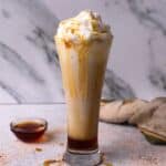 Caramel frappuccino with coffee in tall glass.
