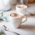 smooth coffee flavored mousse in small white cup with spoon alongside.