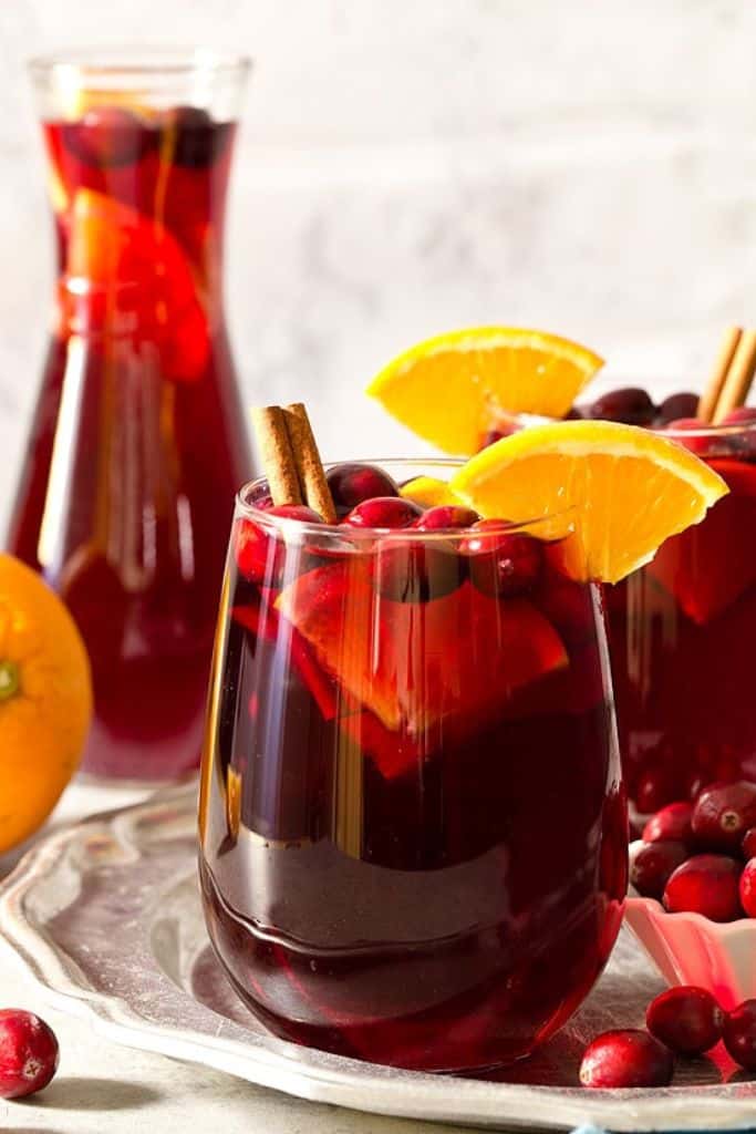 cranberry red sangria in glass with festive garnish.