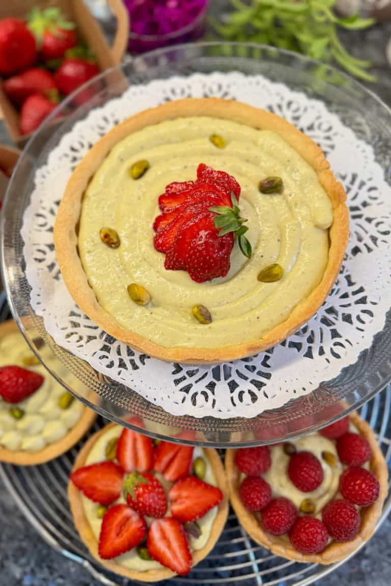 individual pistachio cream tarts with berries.