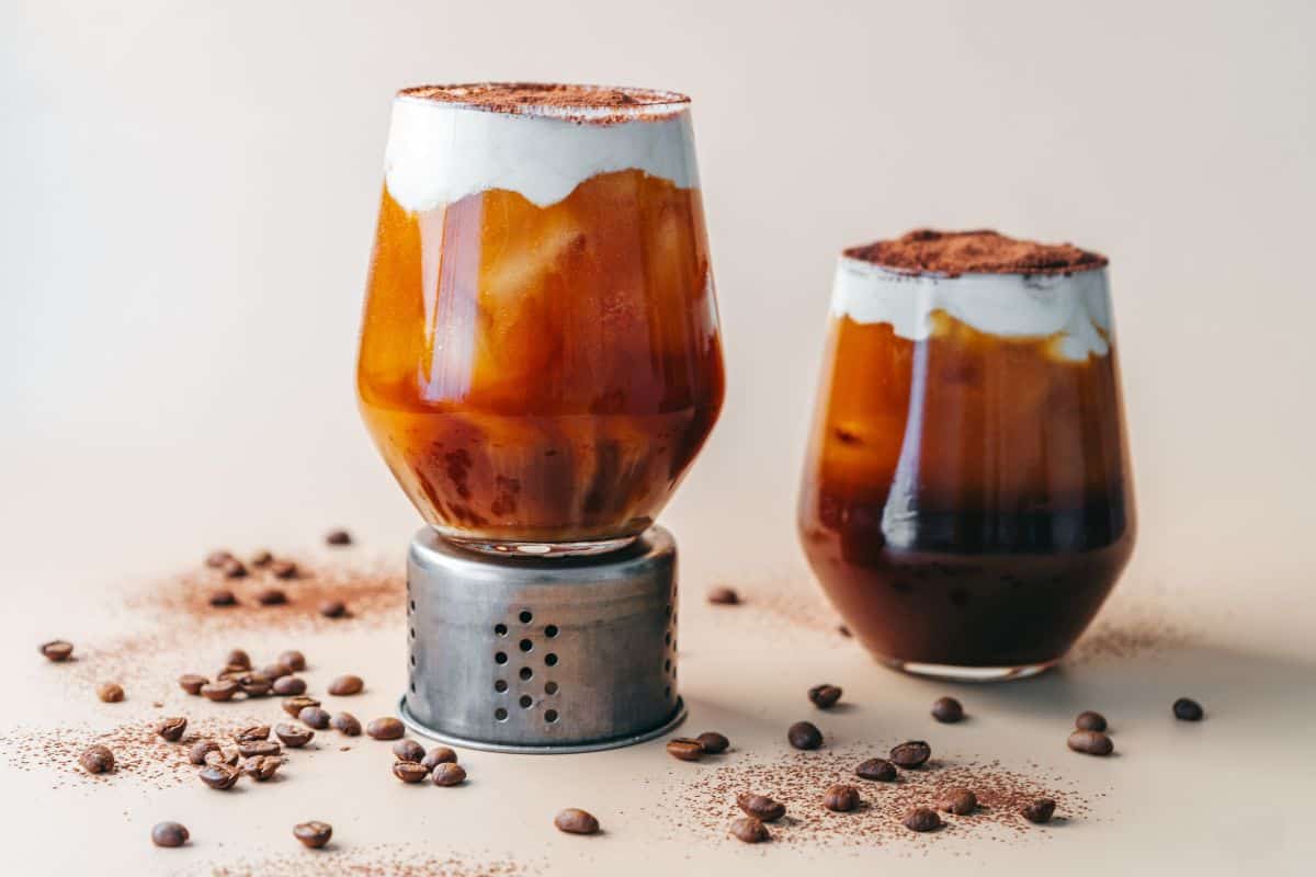 tiramisu cold brew coffee drink in glass surrounded by coffee beans.
