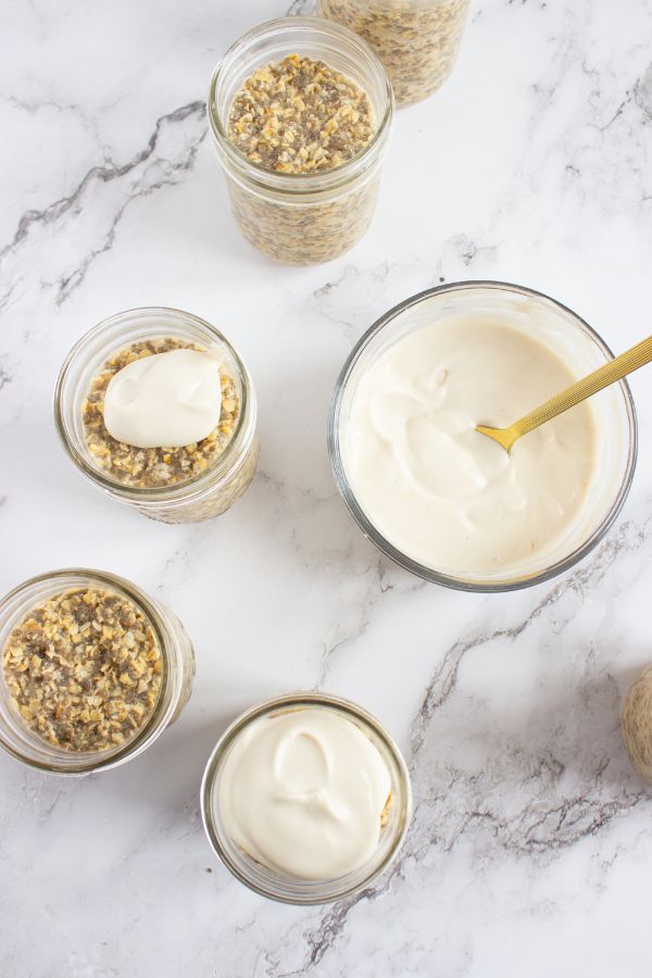 adding greek yogurt to tiramisu overnight oats in jars.