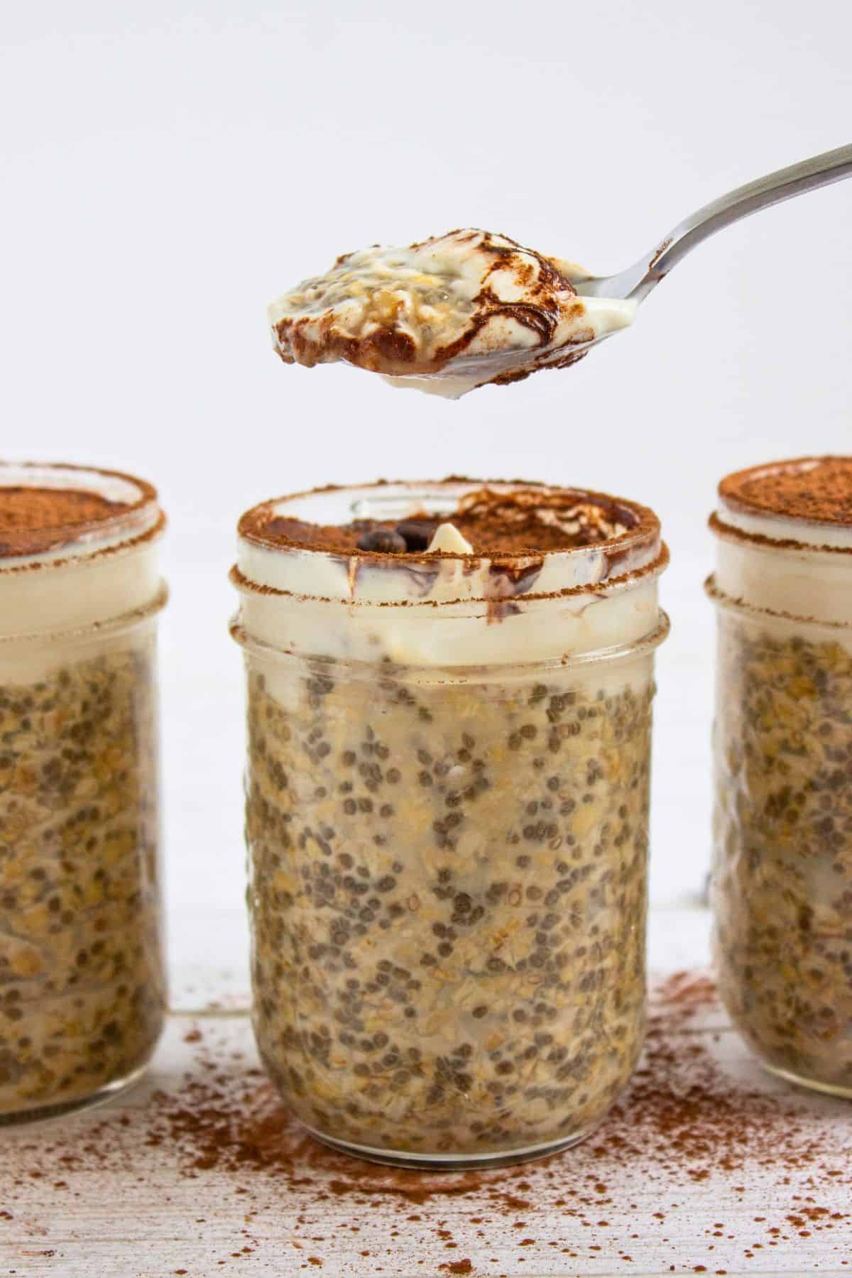 tiramisu overnight oatmeal in a jar with scoop on spoon above.