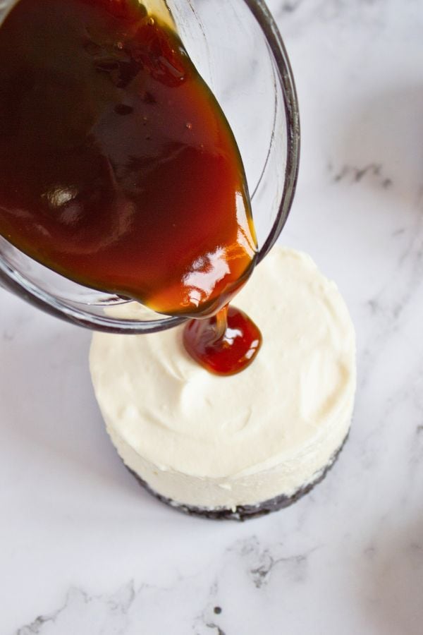pouring coffee syrup on individual cheesecake.