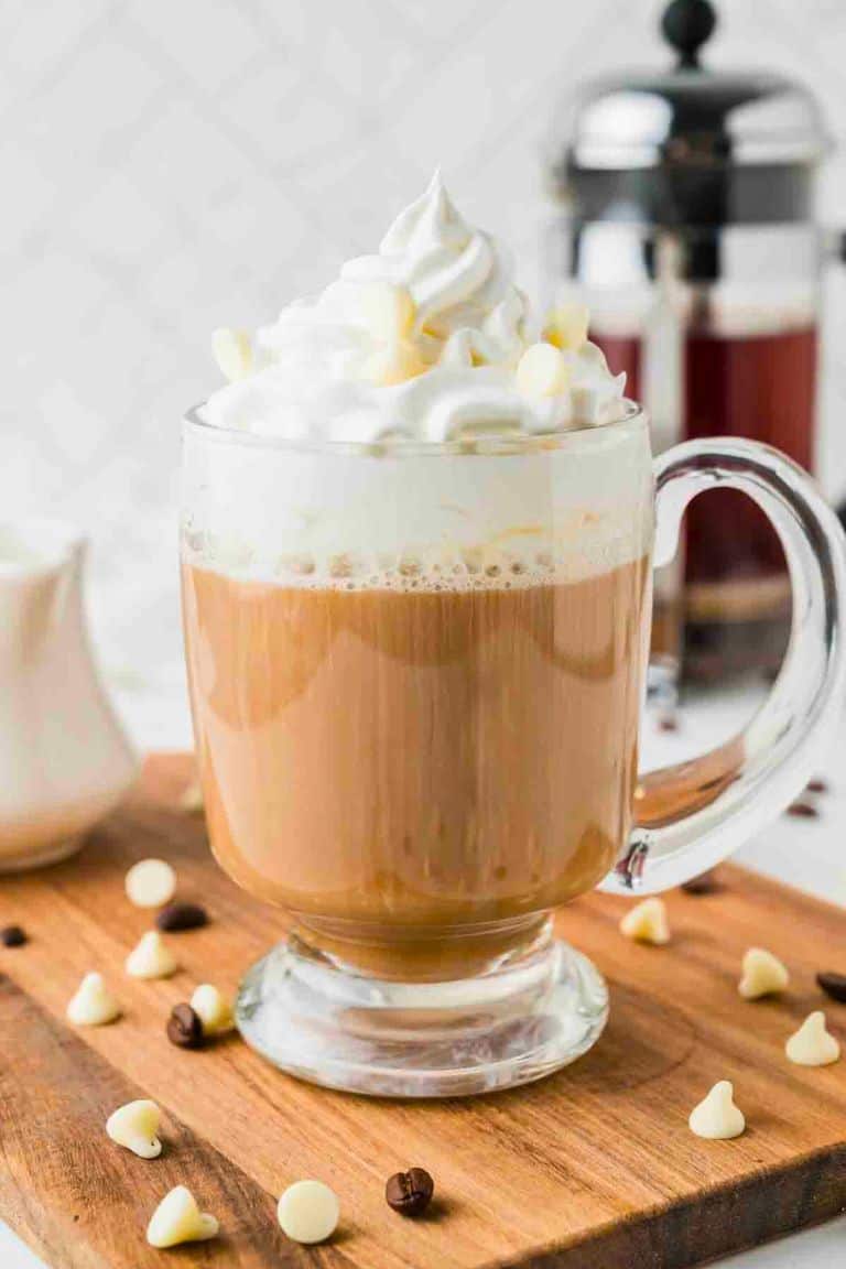 white chocolate latte topped with whipped cream in glass mug.