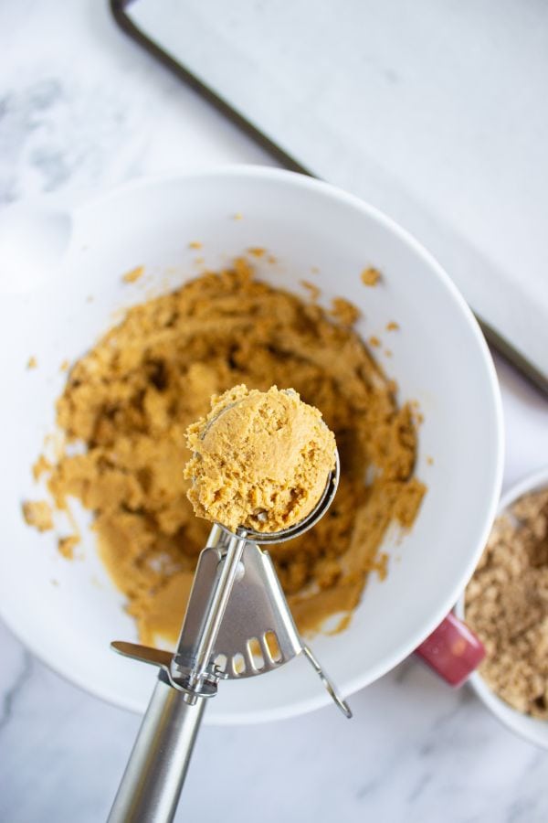 scooping pumpkin cookie mixture from bowl.