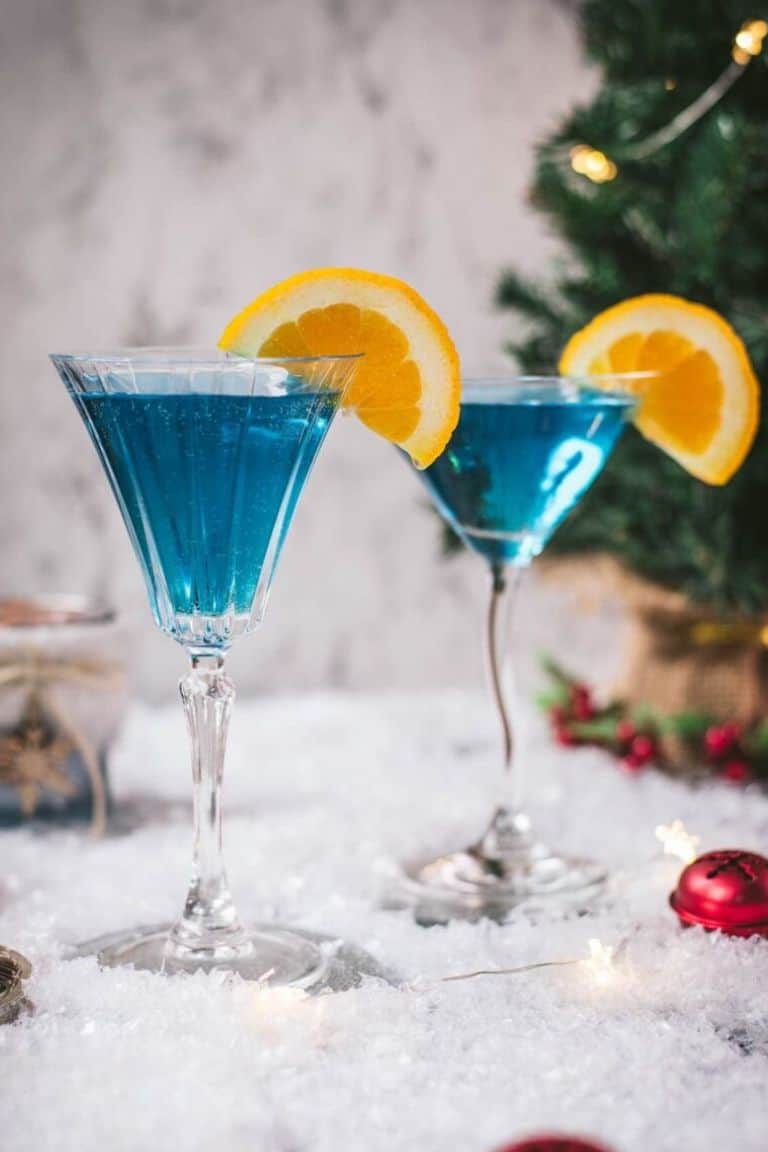 blue christmas party cocktail with orange garnish.