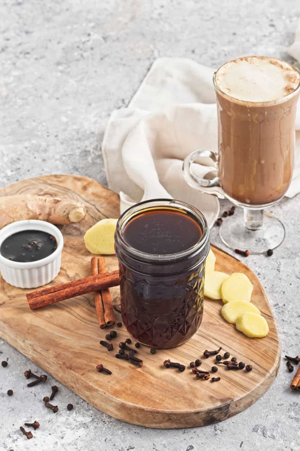 gingerbread coffee syrup in jar surrounded by ingredients and gingerbread latte.