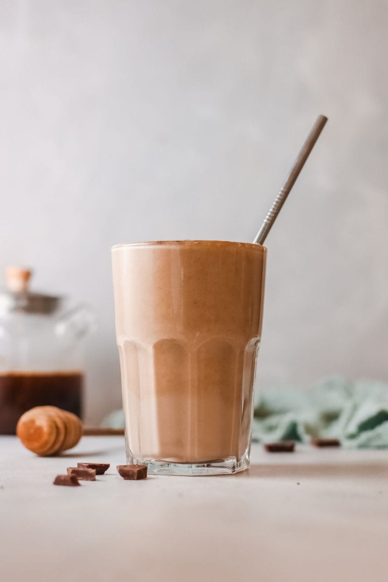 banana coffee smoothie in tall glass with straw.