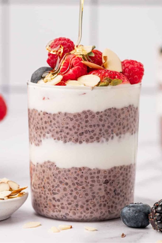berry and yogurt chia pudding in jar with fruit toppings.