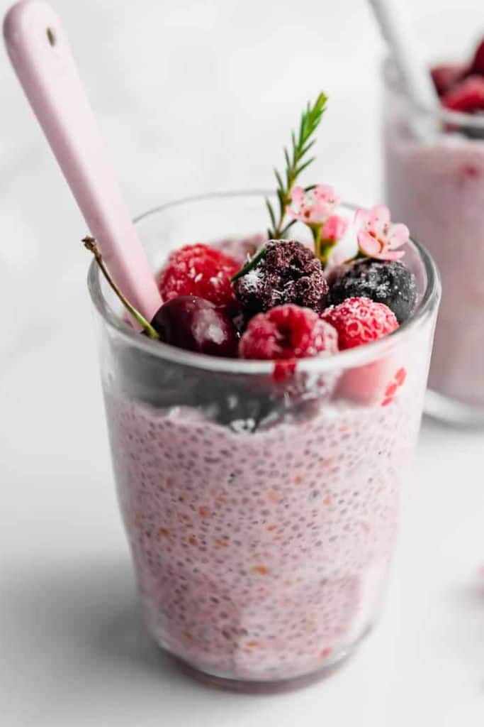 berry chia seed pudding in jar with mixed fruit toppings.