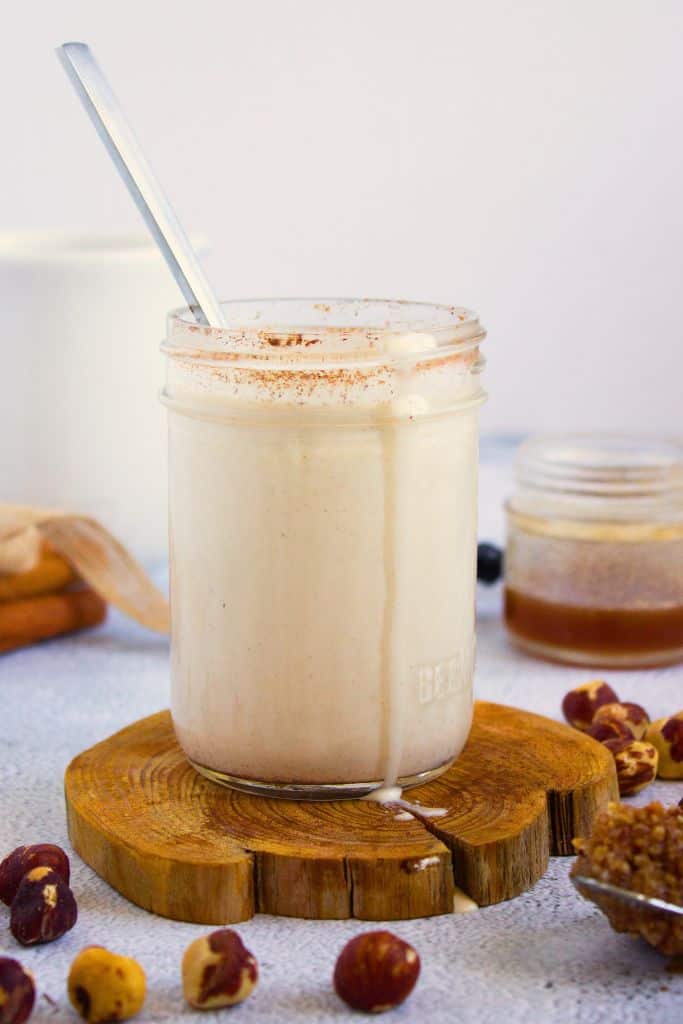 hazelnut coffee creamer in jar surrounded by whole hazelnuts.