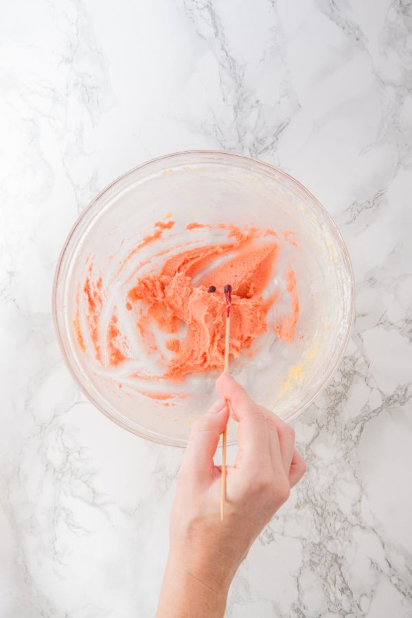 adding food color to make pink cookie dough in bowl.