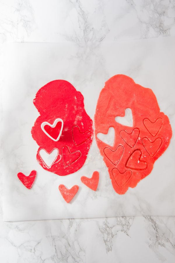 heart shaped cookies cut out of pink dough.
