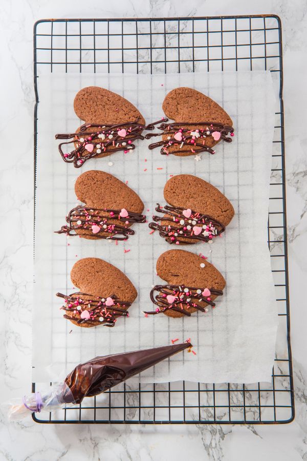 chocolate cookies with pink sprinkles on wire rack.