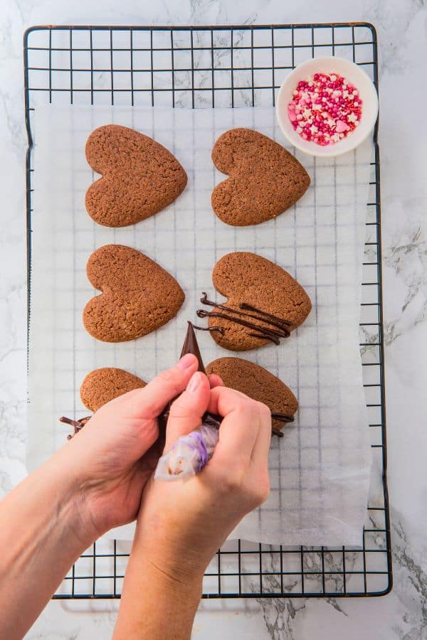 decorating chocolate love cookies with melted chocolate.