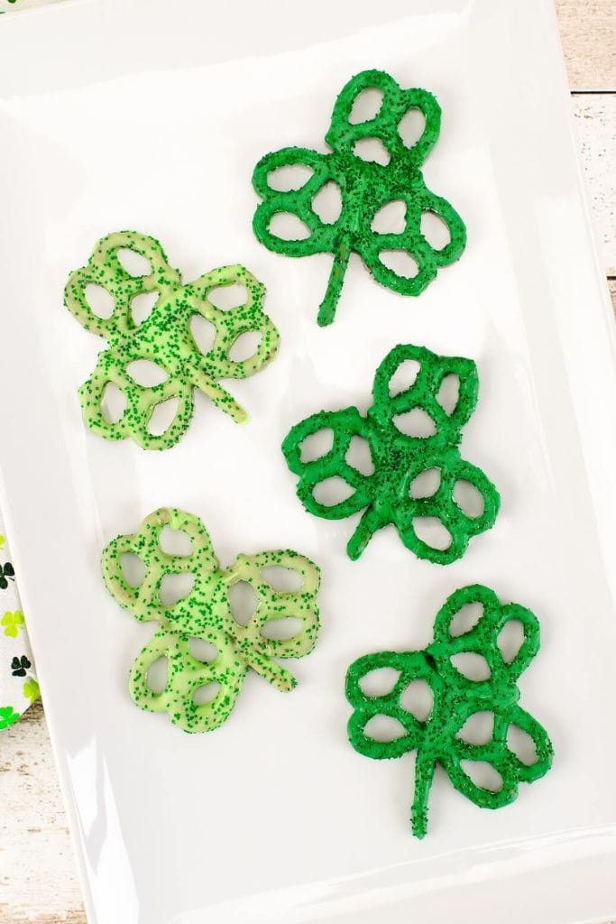 green shamrock pretzel treats on white platter.