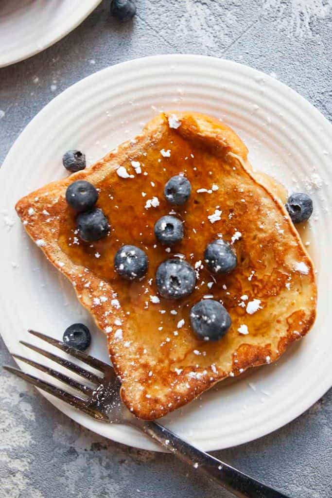 slice of challah french toast with syrup and blueberries.