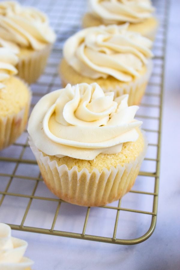 vanilla frosted cupcakes on wire rack.