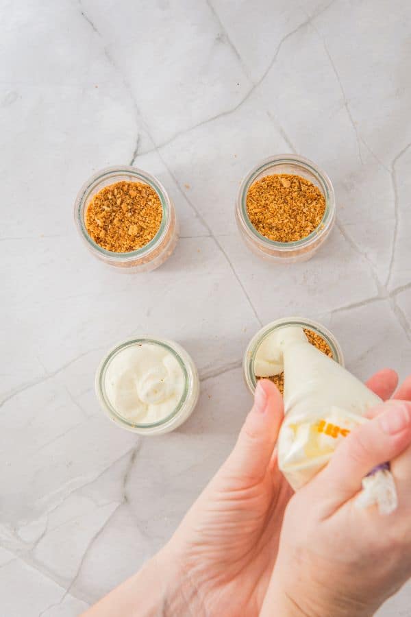 assembling cheesecake cups with lime cream layer.