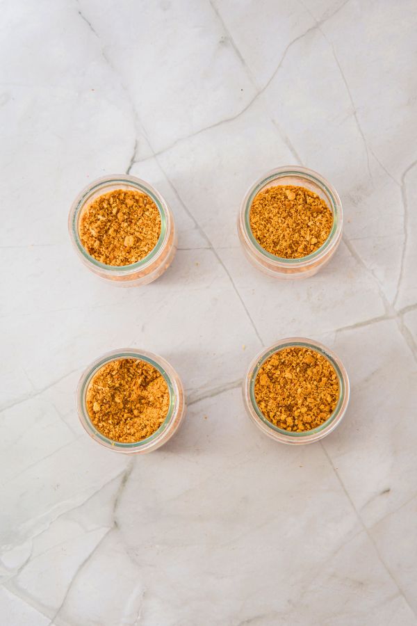 assembling dessert cups with graham cracker mixture.