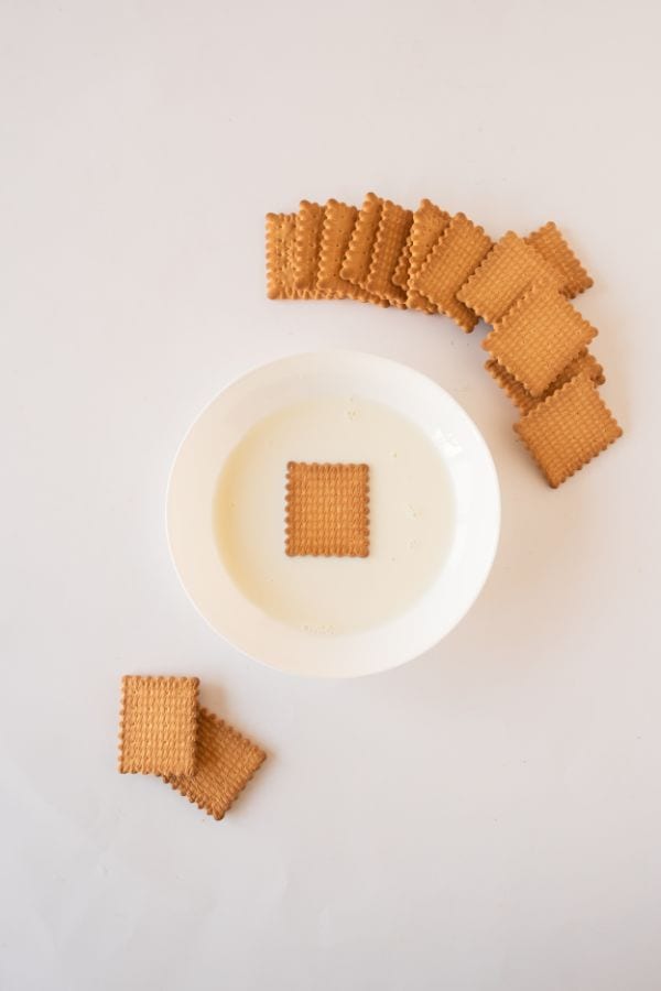 soaking tea biscuits in milk for biscuit cake.