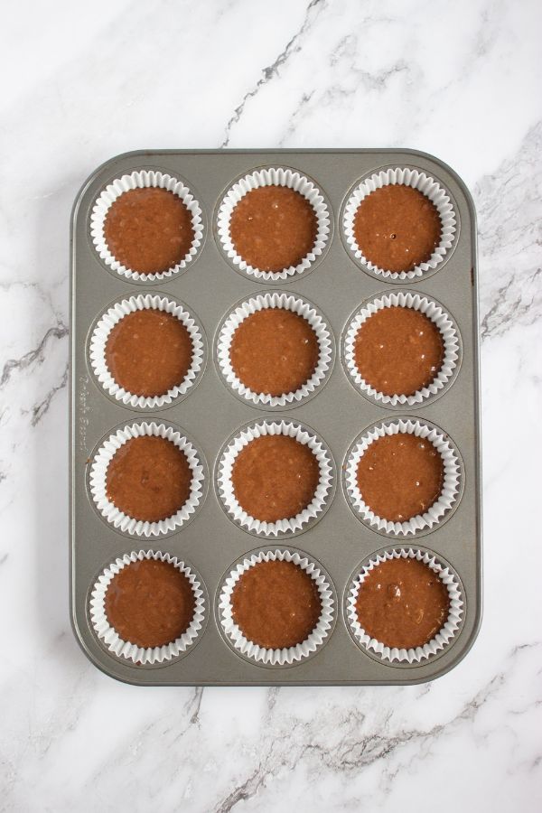 chocolate cupcake mixture in muffin liners in tray.