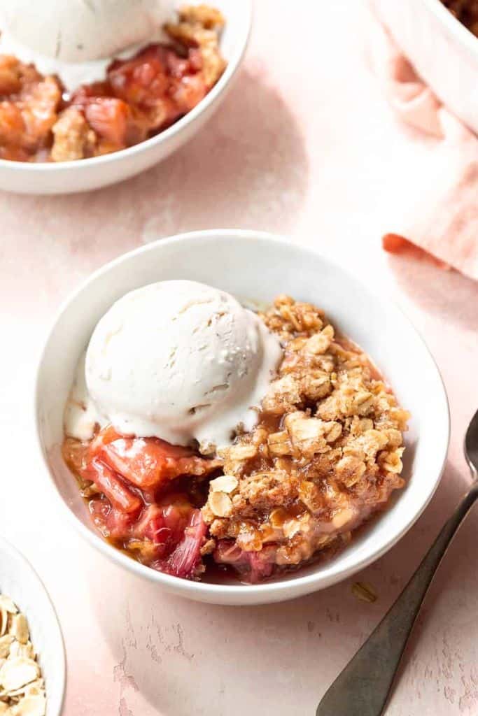 serve of rhubarb crisp in bowl with ice cream.