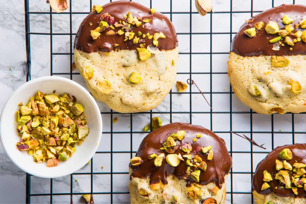 gourmet pistachio cookies on rack with bowl of crushed pistachios.