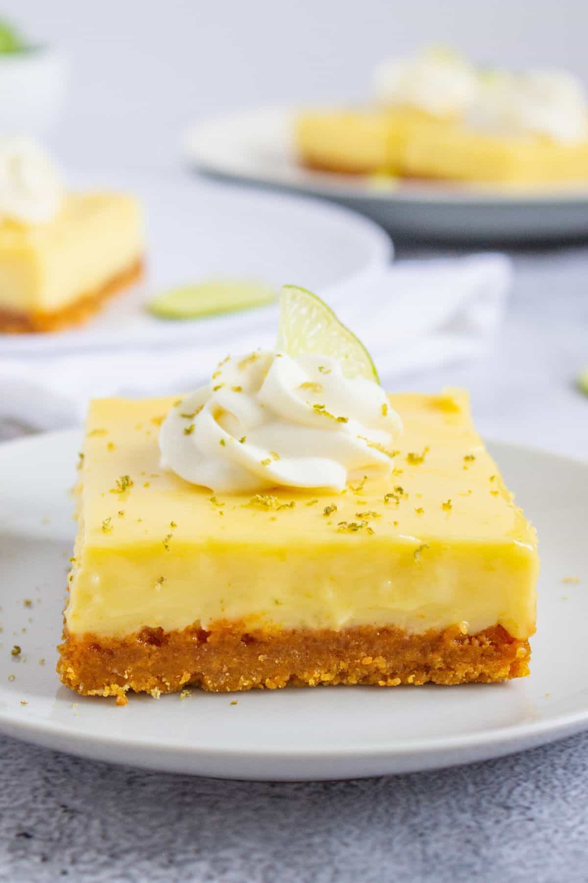 key lime pie bar with cream and slice of lime on plate.