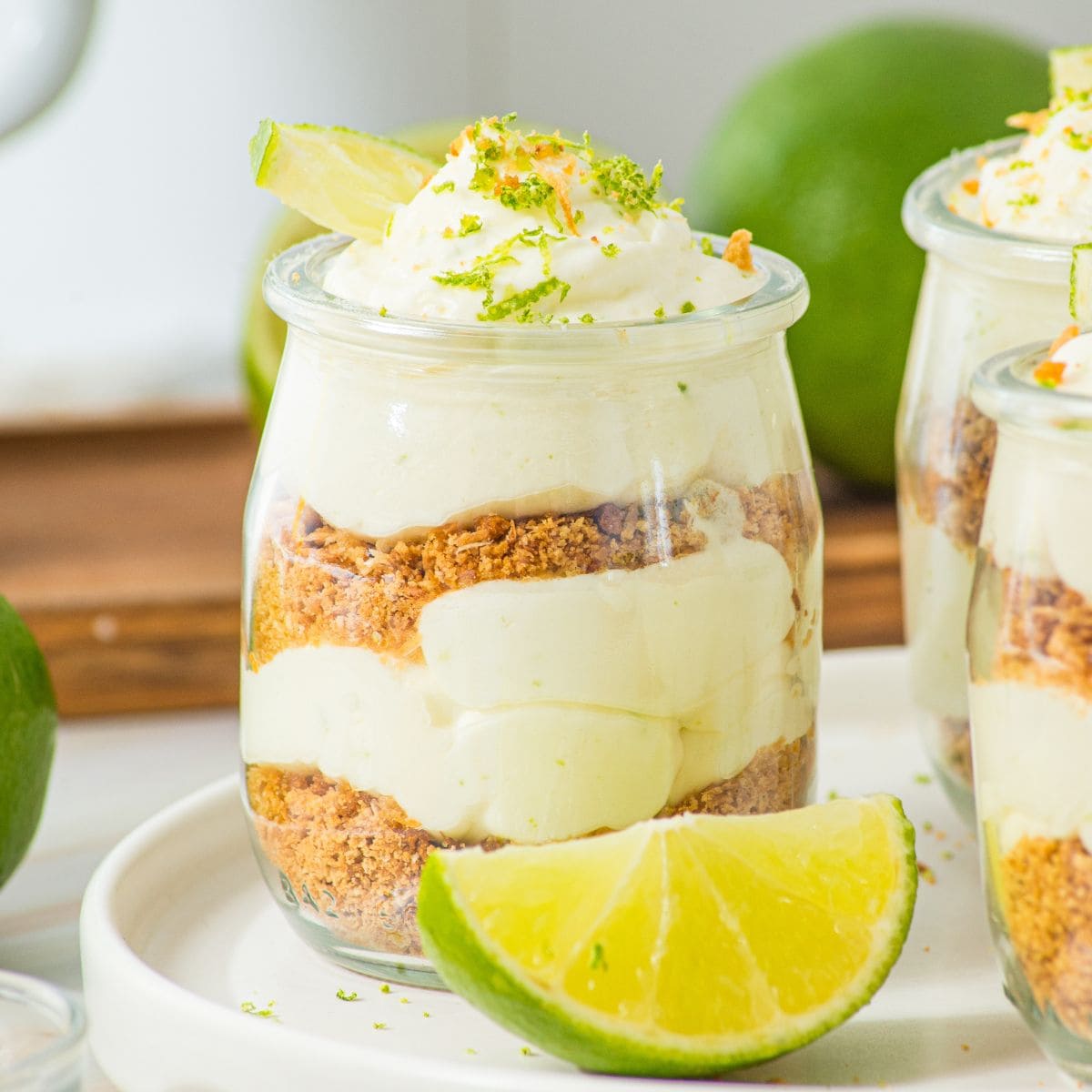 key lime cheesecake cup on plate alongside a slice of lime.