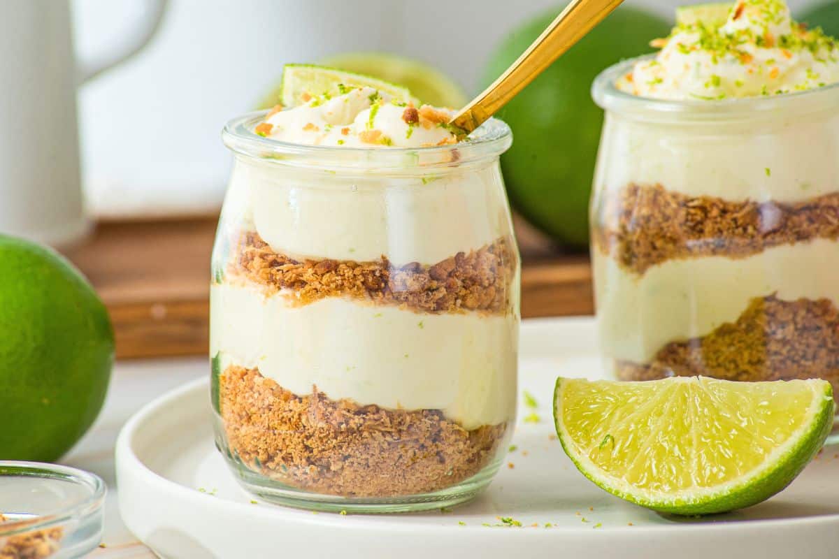 key lime mini cheesecake cups on white plate with gold spoon.