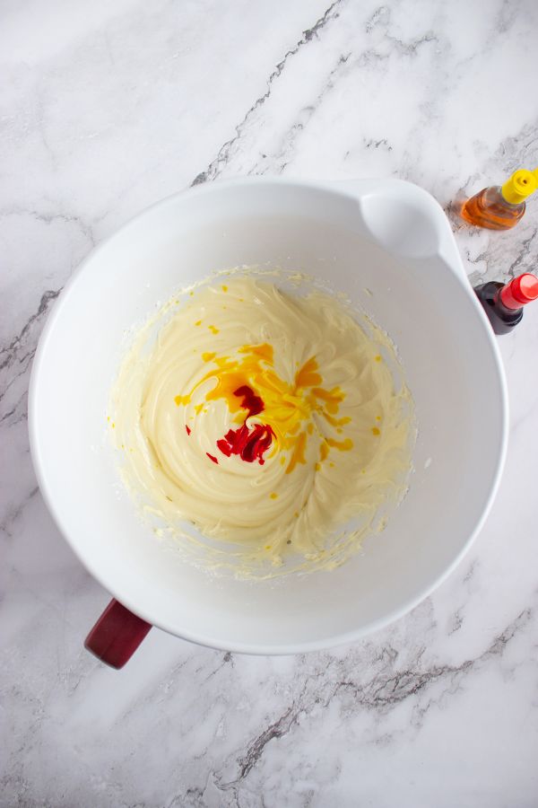 adding food coloring to cream cheese frosting to make fire frosting.