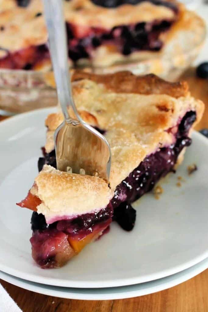 slice of blueberry and peach pie on plate.