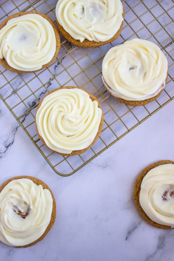 piping cream cheese frosting on top of graham cracker cookies.