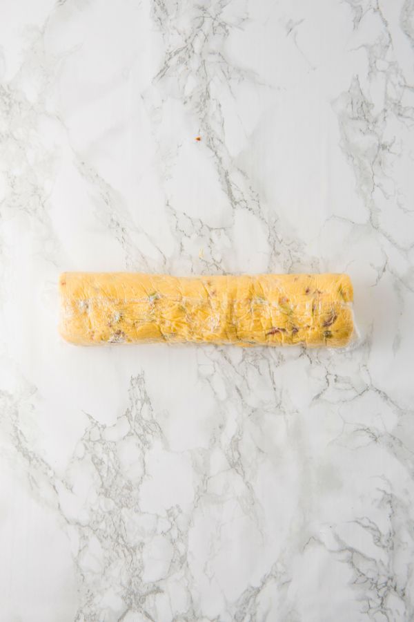pistachio cookie dough roll wrapped in plastic wrap.