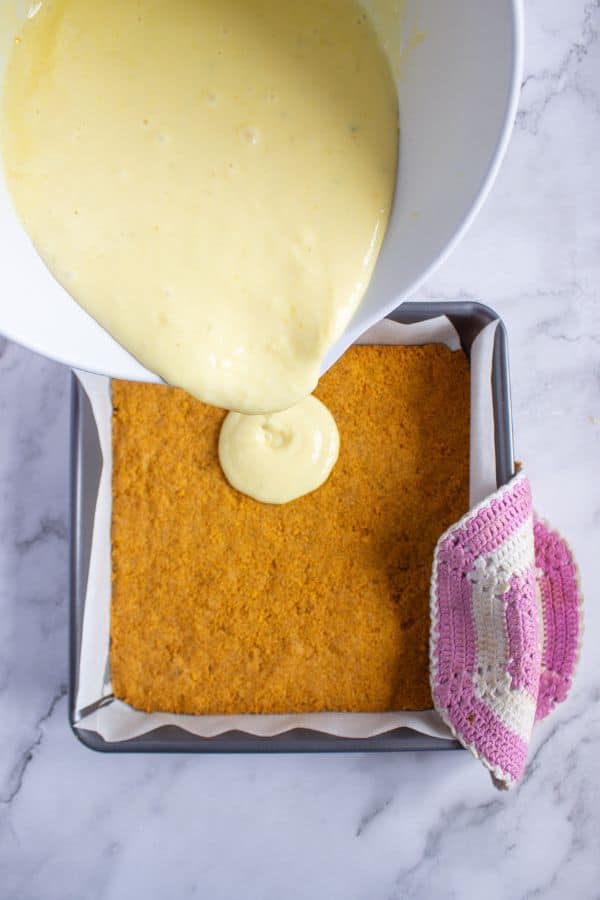 pouring key lime pie filling on to pie crust.