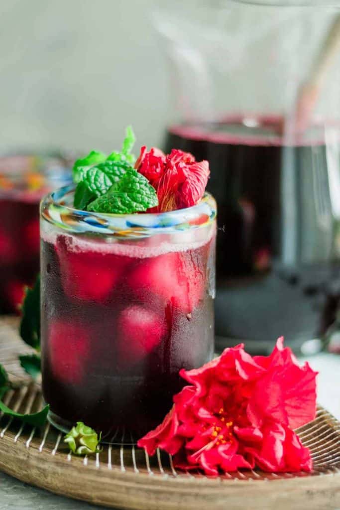 iced hibiscus tea in glass with fresh herbs.