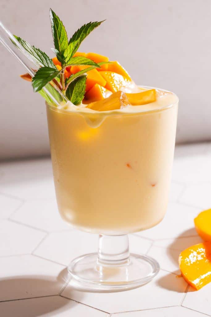 mango lassi in glass with fresh mango.