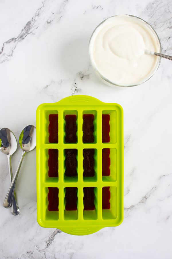 green popsicle mold alongside bowl of yogurt.