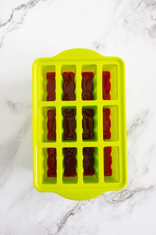 Green popsicle mold with strawberry mixture inside