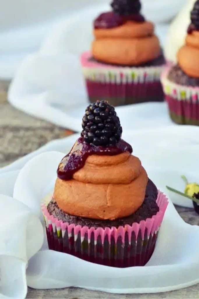 frosted chocolate cupcake with blackberry sauce.
