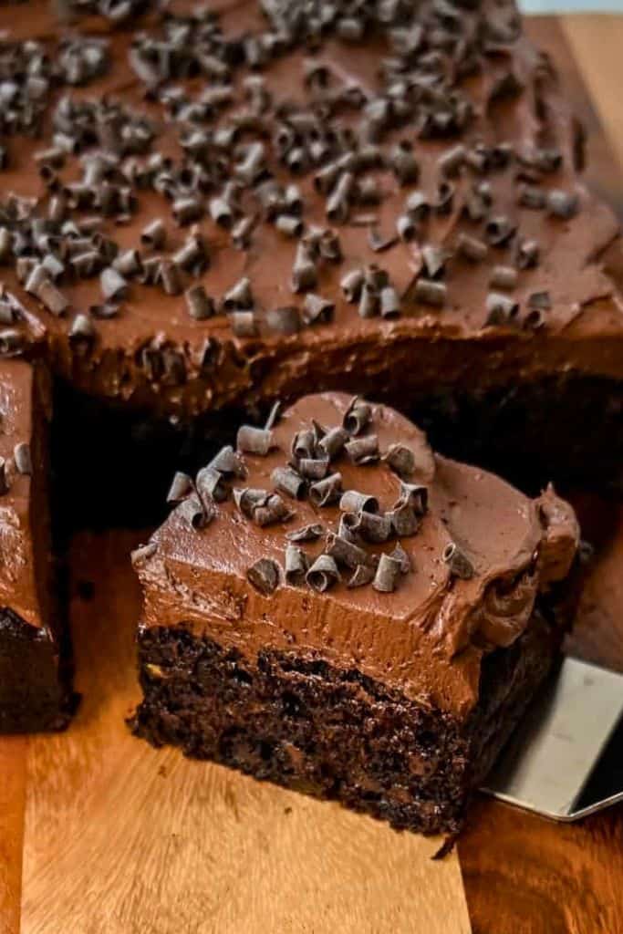 frosted zucchini chocolate cake on wooden board.