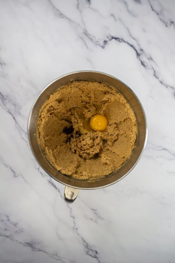 egg in bowl with cookie ingredients.