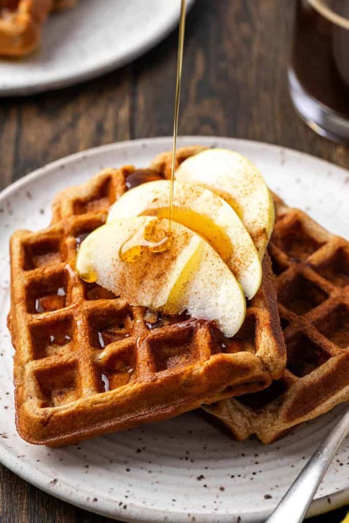 apple cinnamon waffles on plate with pieces of apple.