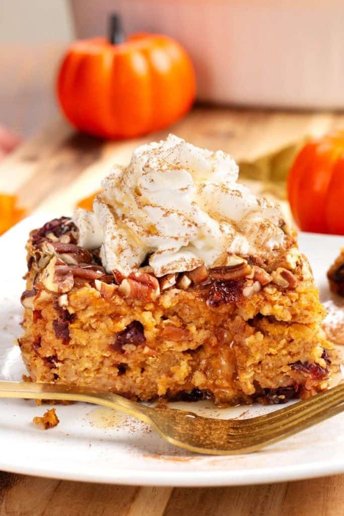 slice of baked pumpkin oatmeal topped with cream on plate.
