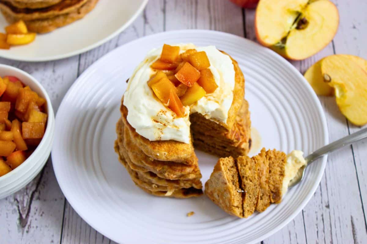 stack of apple pancakes on plate with yoghurt and apple toppings.