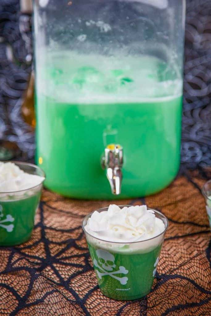 happy potter green polyjuice in drink dispenser and cup with whipped cream.